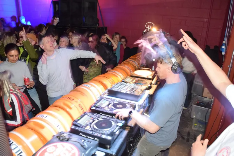 Wide shot of the party: Bring The Beat Mack at the decks, the crowd and the sound system behind