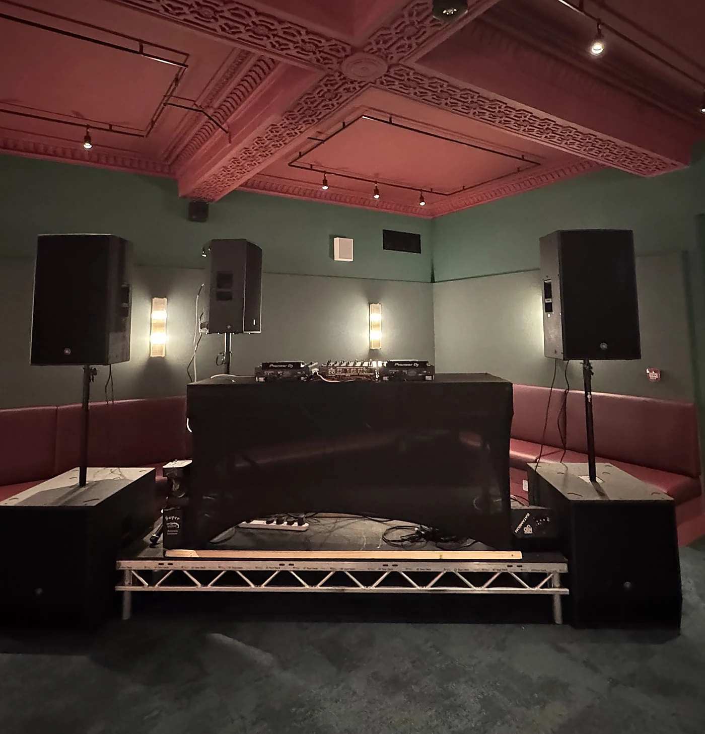 The Upgraded Sound System set up in a venue: Yamaha tops on stands over two subs, a booth monitor, and Pioneer decks on a DJ riser