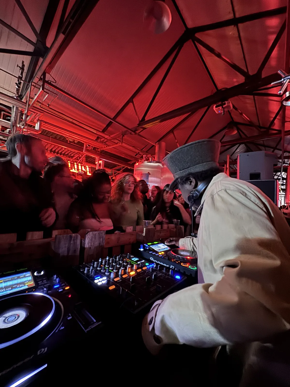 Norman Jay DJing on the Upgraded Sound System decks to a packed crowd under red lights